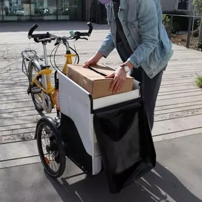 Personne remplissant un velo utilitaire avec une boîte en carton