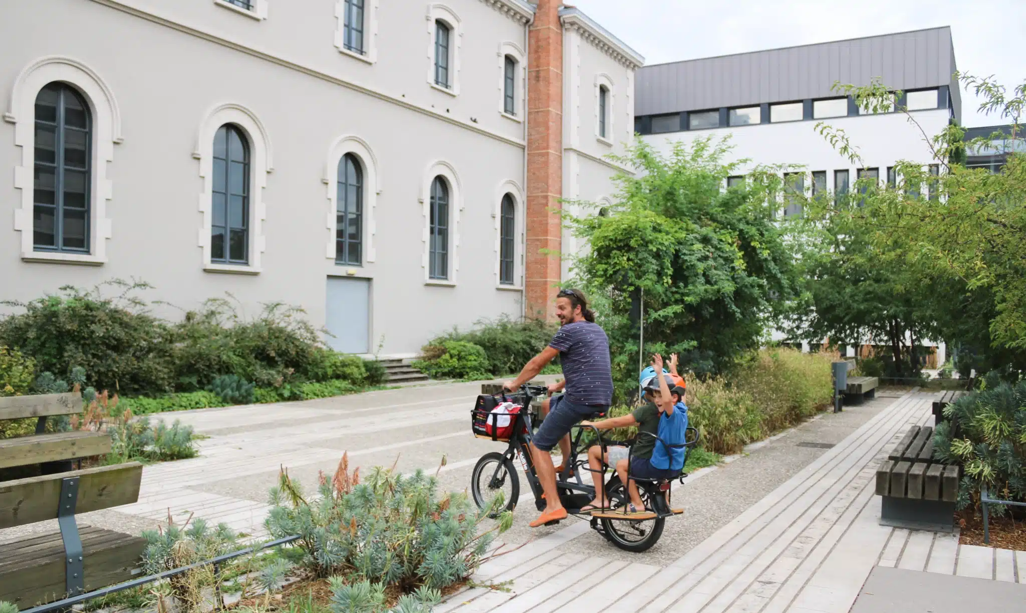 Dad with two boys cycling in a park on a cargo bike