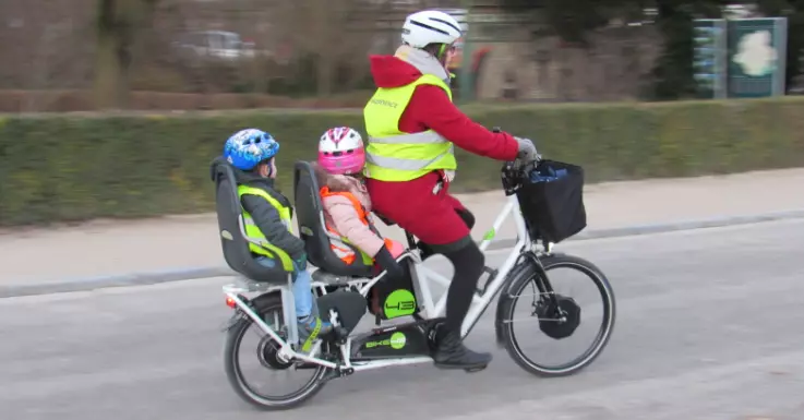 Un parent et deux enfants sur un velo long tail
