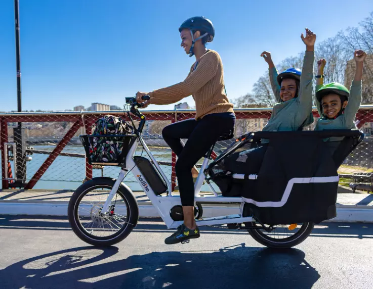 Une mère avec ses deux enfants s'amusant sur un vélo long tail 