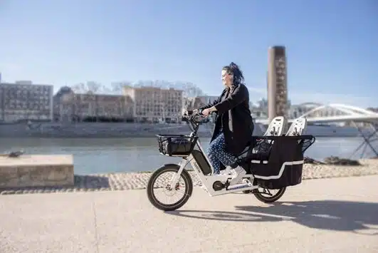 Junge Frau auf einem E Cargo Bike am Wasser