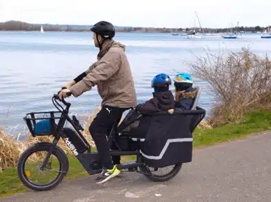 Ein Vater und seine Kinder auf einem Fahrradfahren mit Kindern, der einen See betrachtet