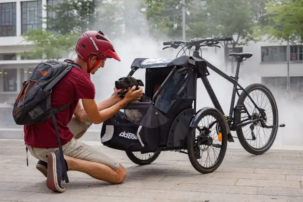 Bike dog carrier kit: medium dog sits in the Dog Kit cargo bike while owner cuddles him