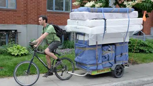 Une remorque vélo charge 100 kg qui transporte un matelas et des meubles