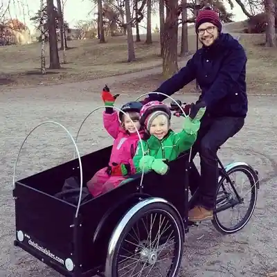 Deux enfants de moins de 12 ans portant un casque dans un triporteur velo