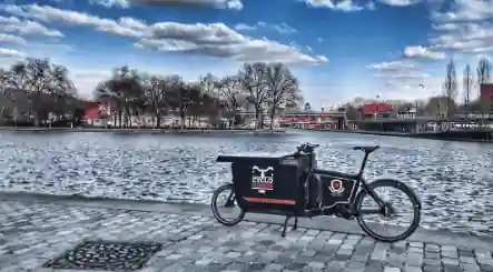 Le vélo cargo électrique professionnel d'un plombier devant un fleuve